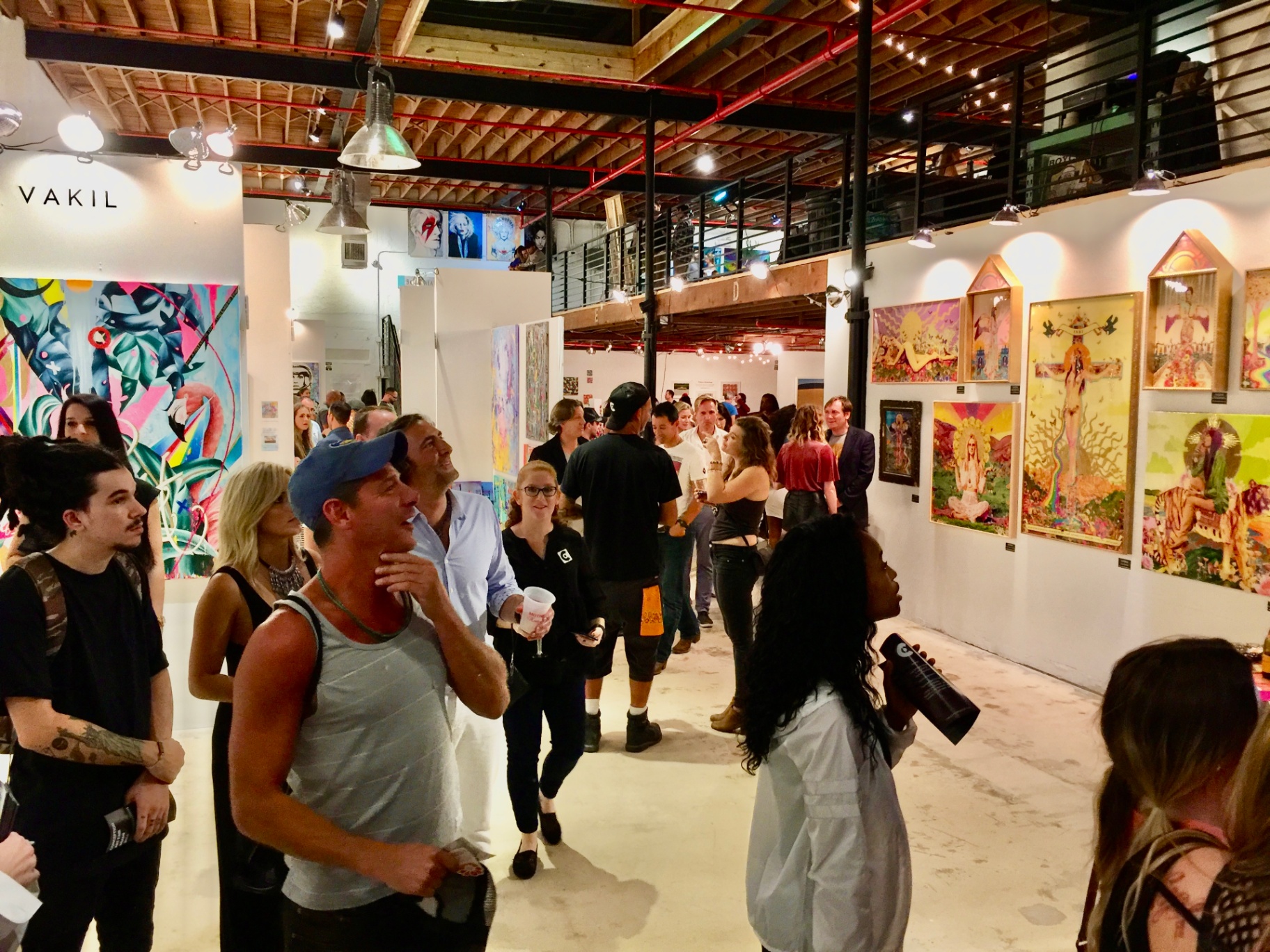 Crowded gallery event with artwork on the walls